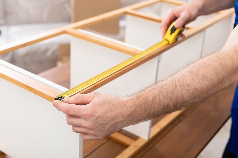 Unrecognizable Man Working Measuring Shelf With Tape Making Furniture Indoor