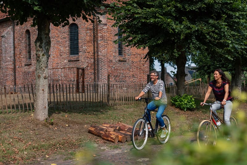 Stel fietst langs een kerk