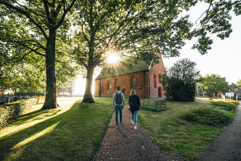 2 personen lopen bij de kerk van Zweeloo