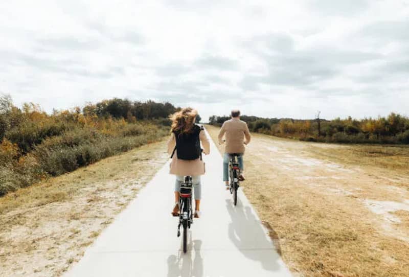 Twee personen fietsen door een open landschap.