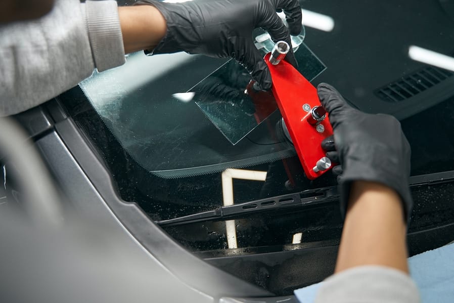 Skilled worker mounting crack repair device on windshield